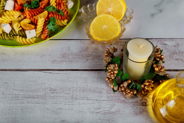 Festliches Weihnachtsessen mit bunten Nudeln, Kirschtomaten, Zitrone und Kerze