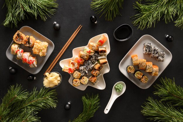 Festliches Weihnachtsessen mit Sushi-Set mit Weihnachtsdekoration auf Schwarz. Neujahrsparty.