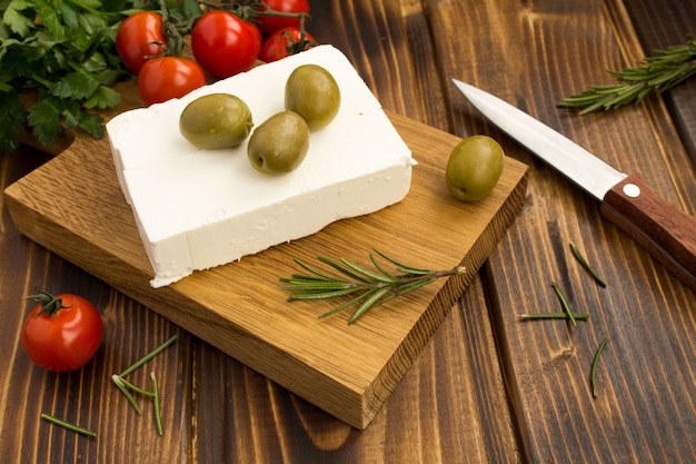 Feta de queijo grego caseiro com azeitonas verdes e cereja na tábua de madeira