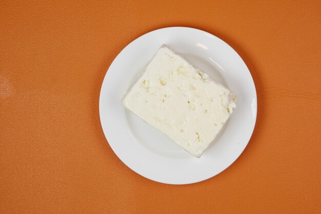 Feta-Käse auf einem Teller auf orangefarbenem Hintergrund