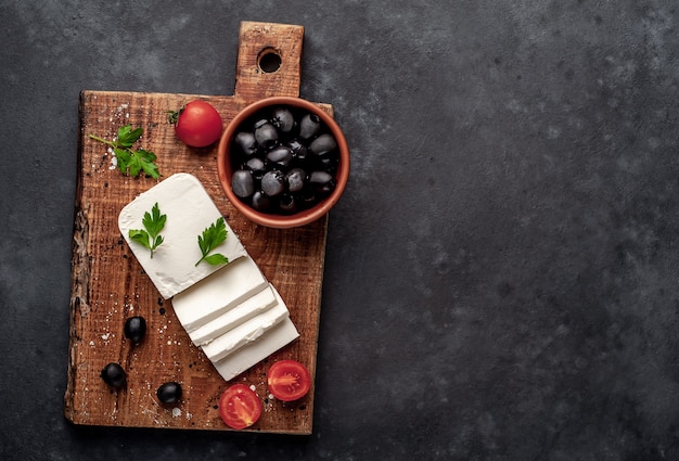 Feta-Käse, mit Rosmarin, Tomaten, Oliven auf einem Steinhintergrund. Draufsicht mit Speicherplatz für Ihren Text