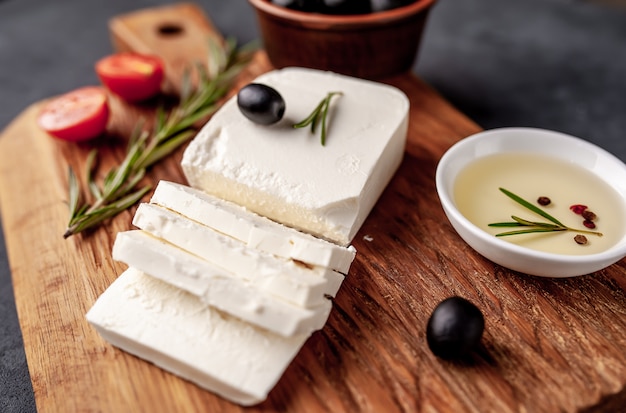 Feta-Käse, mit Rosmarin, Tomaten, Oliven auf einem Steinhintergrund.