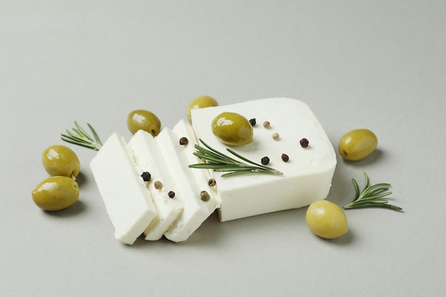 Feta-Käse, Oliven, Rosmarin und Pfeffer auf grauer Oberfläche
