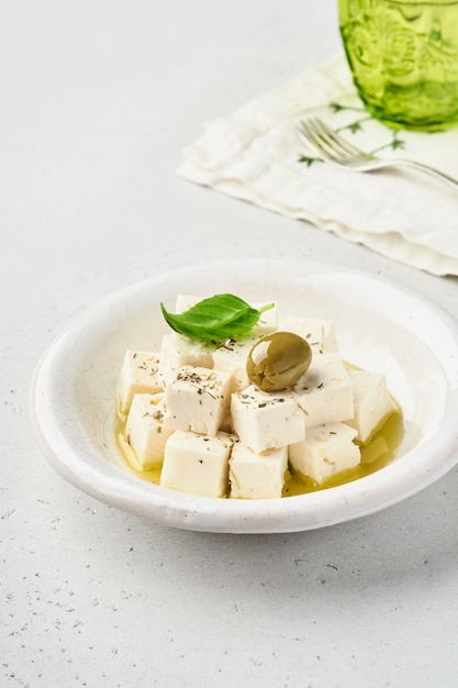 Feta-käsewürfel mit rosmarin, oliven und olivenölsauce in weißer schüssel