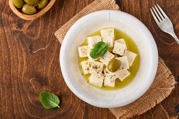 Feta-Käsewürfel mit Rosmarin, Oliven und Olivenölsauce in weißer Schüssel