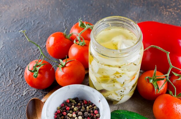 Feta marinado picante en una jarra y verduras para ensalada.