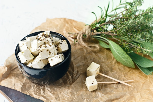 Feta marinado en un plato sobre una tabla de madera con especias sobre un fondo blanco