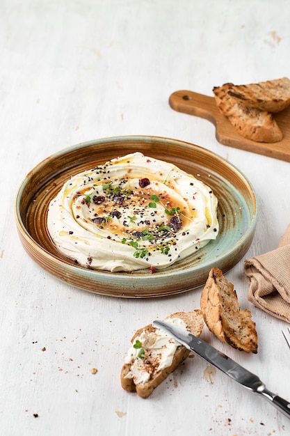 Feta mit Kräutern, würzigem Honig und Minibaguette auf einem Teller. vegetarisches Menü, gesundes Essen.