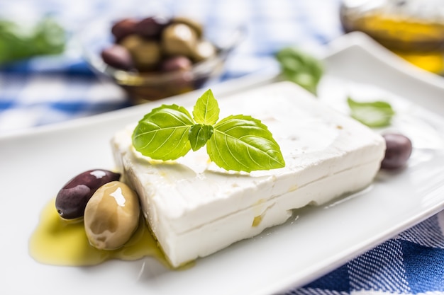 Feta de queso griego con aceitunas de aceite de oliva y hojas de albahaca.