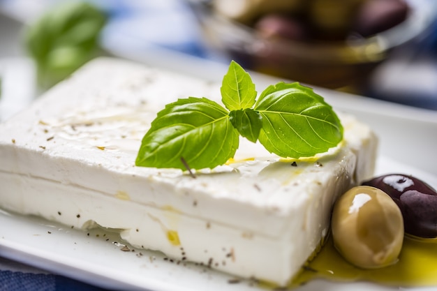 Feta de queso griego con aceitunas de aceite de oliva y hojas de albahaca.