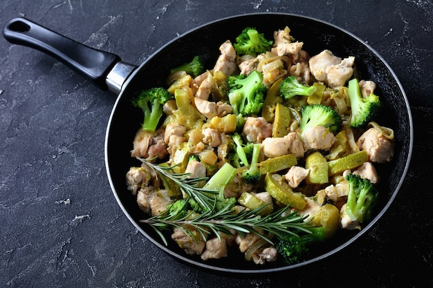 Fettarmes Abendessen gebratenes Hühnerfleisch mit grünem Gemüse: Zucchini, Brokkoli, Zwiebel und Rosmarin auf einer Pfanne