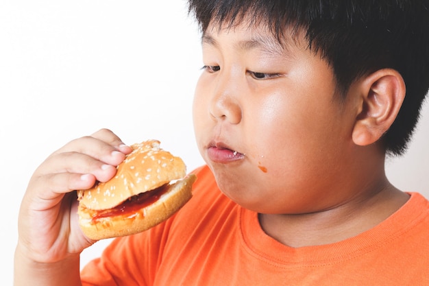 Fette asiatische Kinder essen Hamburger. Lebensmittelkonzepte, die bei Kindern körperliche Gesundheitsprobleme verursachen.