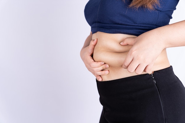 Foto fette frau, die übermäßigen fettbauch hält, lokalisierte grauen hintergrund.