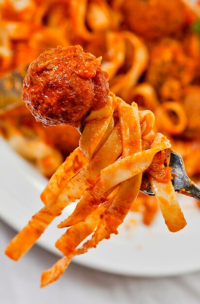 Fettuccine y albóndigas en un tenedor closeup