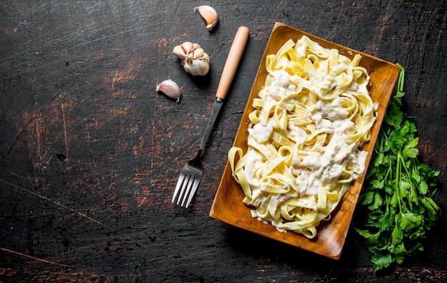 Fettuccine de macarrão com molho Carbonara no prato com alho e salsa