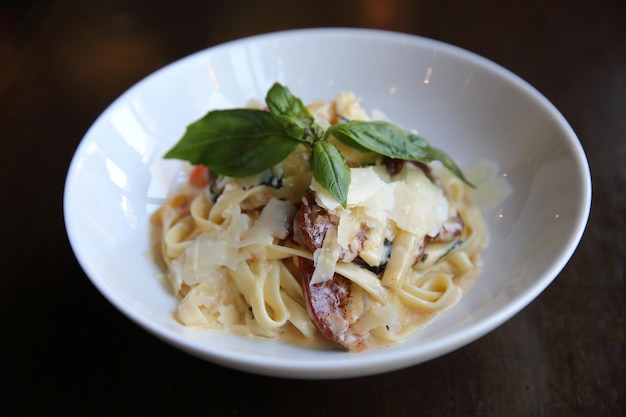 Fettuccine de espaguetis con chorizo sobre fondo de madera