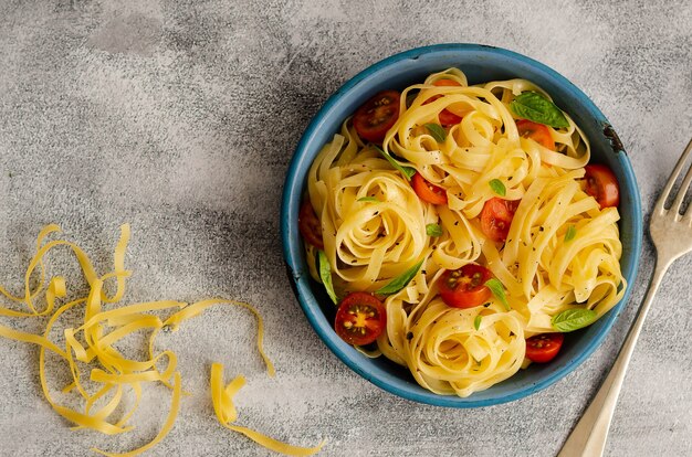 Fettuccine mit geschnittenen Kirschtomaten und Basilikumblättern