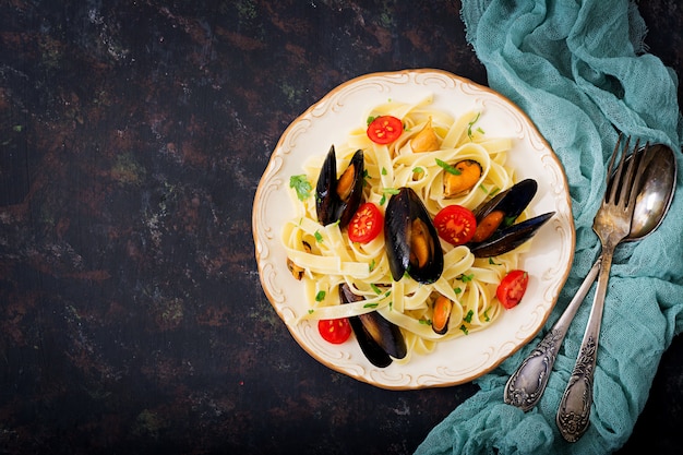 Fettuccine-Nudeln mit Meeresfrüchten und Muscheln über dem schwarzen Tisch. Mediterrane Delikatesse. Flach liegen. Draufsicht