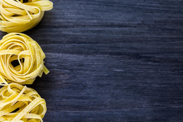 Fettuccine orgánico anida pasta sobre tablero de madera.