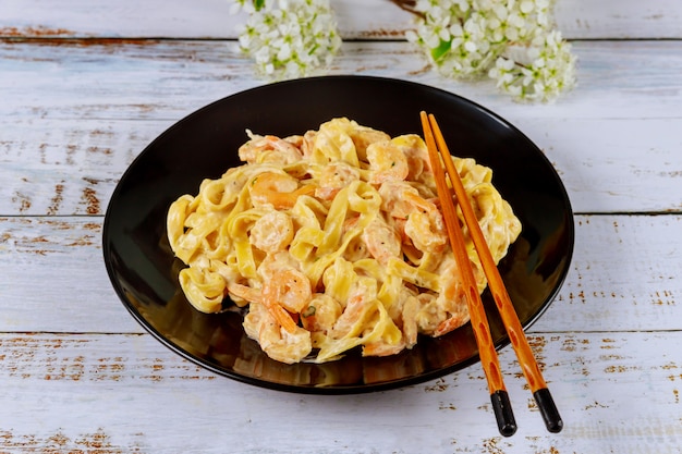 Fettuccine pasta con camarones en placa negra.