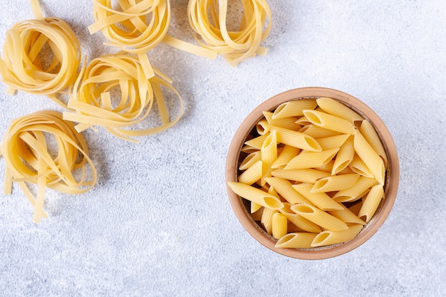 Fettuccine y pasta penne sobre yeso blanco