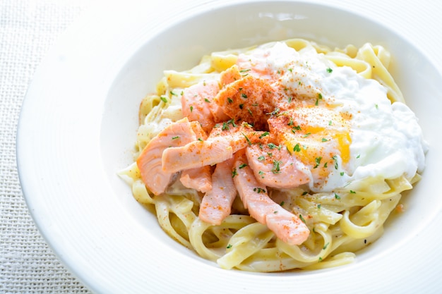 Fettucine con salmón, huevo y queso parmesano, servido en un plato.