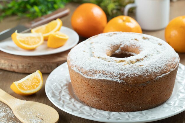 Feuchte Orangenfruchtkuchen auf Teller mit Orangenscheiben auf Holztisch Köstliches Frühstück traditionelle englische Teezeit Orangenkuchenrezept