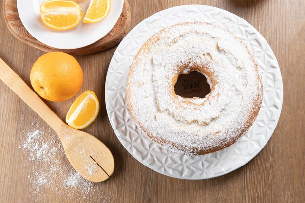 Feuchter Orangenfruchtkuchen auf Teller mit Orangenscheiben auf Holztisch Köstliches Frühstück traditionelle englische Teezeit Orangenkuchenrezept Draufsicht