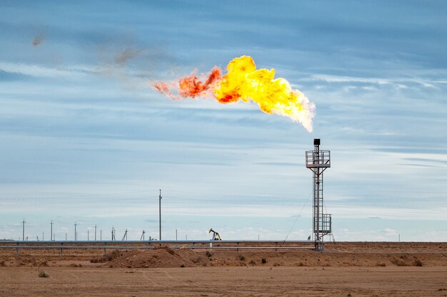 Feuer auf einem Stapel Fackel an der zentralen Öl- und Gasverarbeitungsplattform mit dem blauen Himmel auf dem Hintergrund