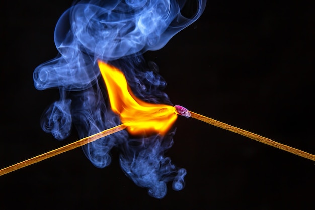 Feuer und Rauch Brennendes und rauchendes Streichholz auf schwarzem Hintergrund Hitze und Licht von der Feuerflamme
