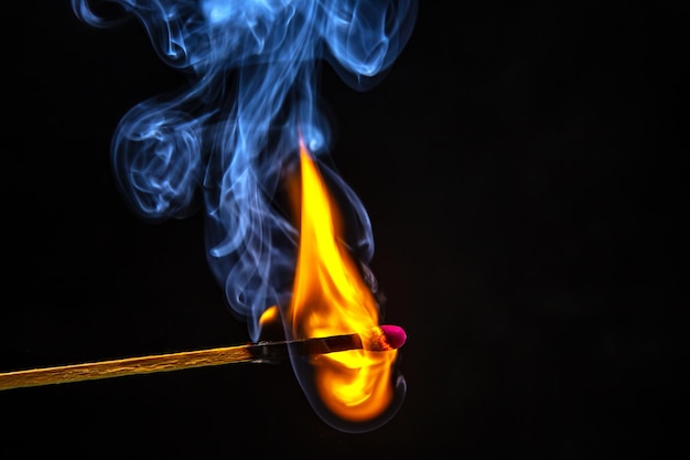 Feuer und Rauch Brennendes und rauchendes Streichholz auf schwarzem Hintergrund Hitze und Licht von der Feuerflamme