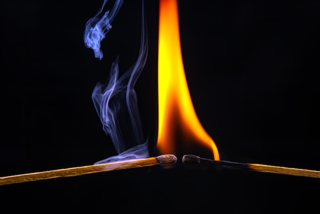 Feuer und Rauch Brennendes und rauchendes Streichholz auf schwarzem Hintergrund Hitze und Licht von der Feuerflamme