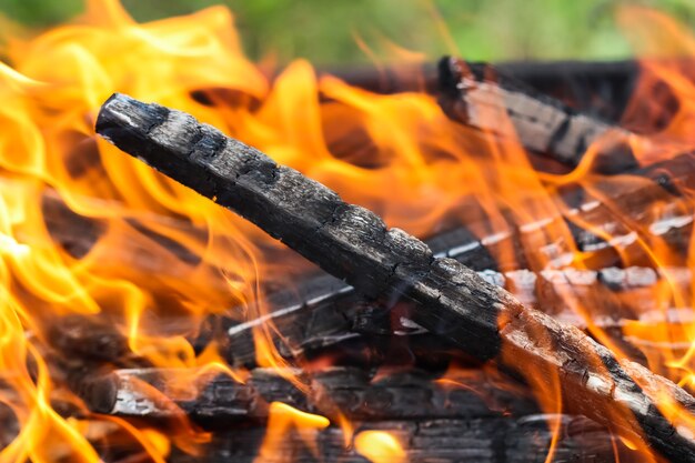 Feuerflammen und heiße Kohlen aus verbranntem Holz