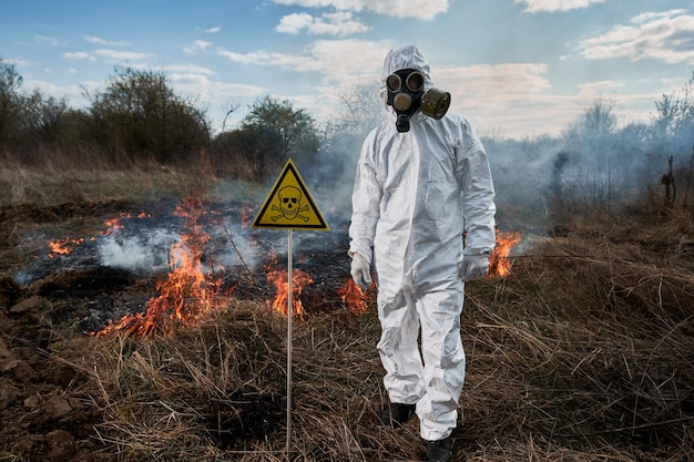 Feuerwehr-Ökologe in Gasmaske, der auf dem Feld mit Waldbränden arbeitet