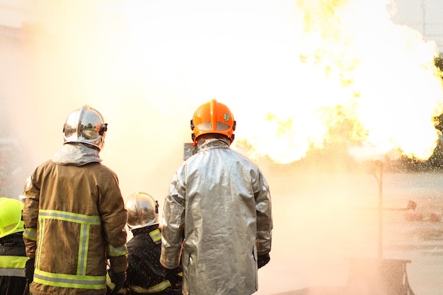 Feuerwehrleute, die einen Feuerlöscher vom Typ Wirbelwassernebel verwenden, um mit der Feuerflamme aus Öl zu kämpfen, um das Feuer zu kontrollieren und sich nicht auszubreiten Feuerwehrmann und Arbeitssicherheitskonzept