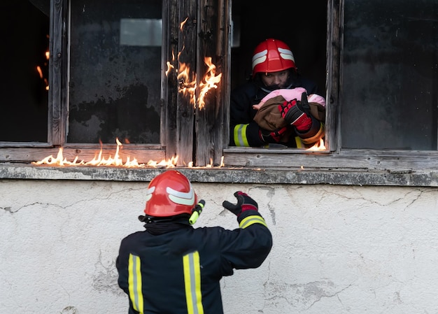 Feuerwehrmann-Held, der ein kleines Mädchen aus einem brennenden Gebäudebereich nach einem Brandvorfall trägt. Retten Sie Menschen aus gefährlichen Orten. Teamarbeit Hochwertiges Foto