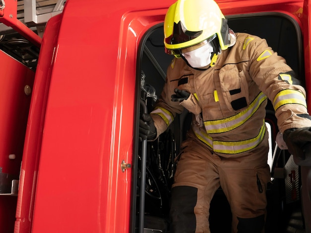 Feuerwehrmann mit Maske beim Aussteigen aus dem LKW mit Interventionsanzug