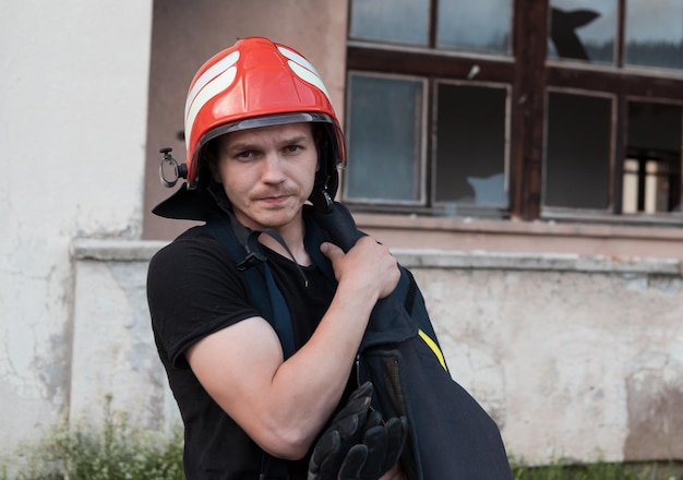 Feuerwehrmann mit Uniform und Helm steht vor Stromkabel auf einem Dach. Foto in hoher Qualität