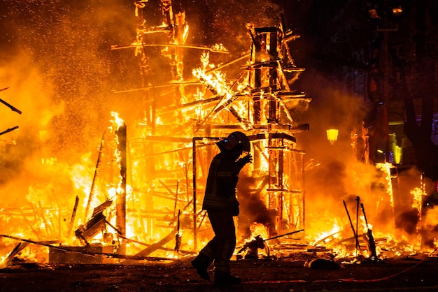 Feuerwehrmann steht in voller Länge gegen das Feuer