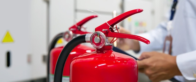 Feuerwehrmann überprüft manometer des roten feuerlöschertanks im gebäude