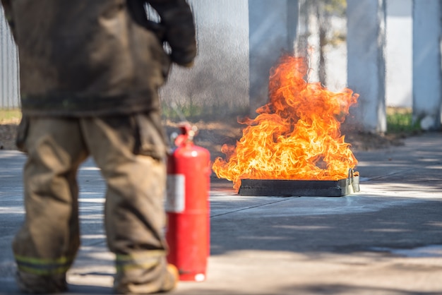 Feuerwehrmann zeigt einen Feuerlöscher an einem trainierenden Hydranten mit weißem Rauch. Arbeitsschutzkonzept.