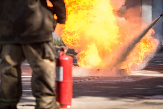 Feuerwehrmann zeigt einen Feuerlöscher an einem trainierenden Hydranten mit weißem Rauch. Arbeitsschutzkonzept.