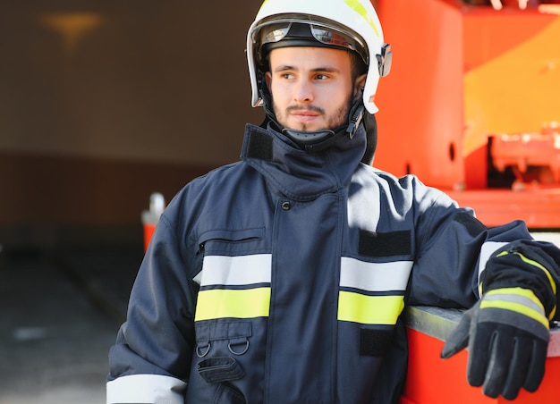 Feuerwehrporträt im Einsatz Foto Feuerwehrmann mit Gasmaske und Helm neben Feuerwehrauto