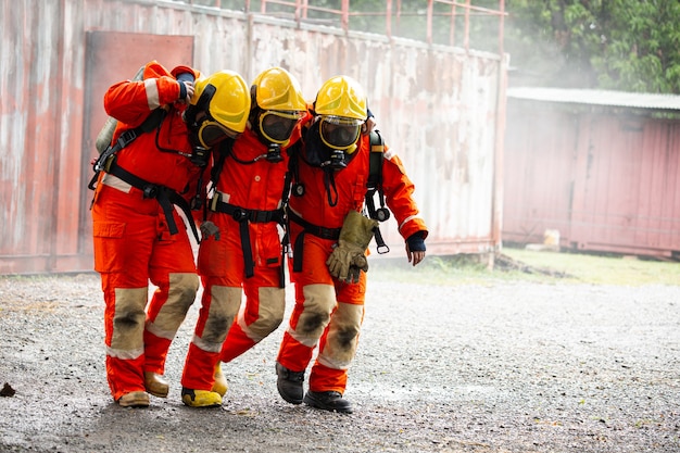 Feuerwehrteam unterstützt Freund nach einem Unfall in einem gefährlichen Bereich. Schutz und Unterstützung gemeinsam. Teamwork-Konzept der kooperativen Vereinigung.