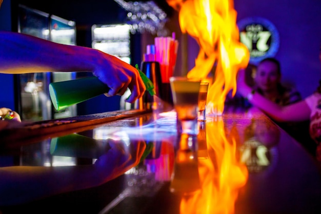 Foto feurige show an der bar. der barkeeper macht einen heißen alkoholischen cocktail und entzündet die bar. feuer auf bar.