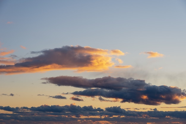 Feuriger orangefarbener Sonnenuntergangshimmel. Schöner perfekter Himmel für Ihre Fotos. Wolkengebilde von Cumulus-Sonnenuntergangwolken mit Sonnenlicht, Abendhimmel. Himmlischer Hintergrund zum Überlagern