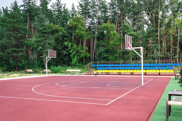 Öffentlicher Basketballplatz im Freien. Ein leerer Sportkomplex am Stadtrand in Waldnähe.