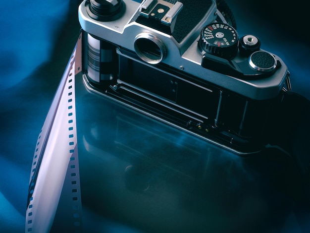 Öffnen Sie alte Vintage-Filmkamera mit Filmstreifen auf abstraktem blauschwarzem Hintergrund