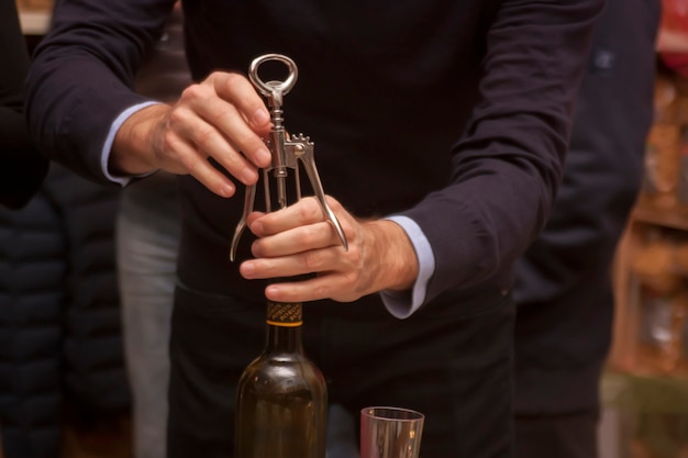 Öffnen Sie auf einer Party eine Flasche Wein mit einem Korkenzieher.