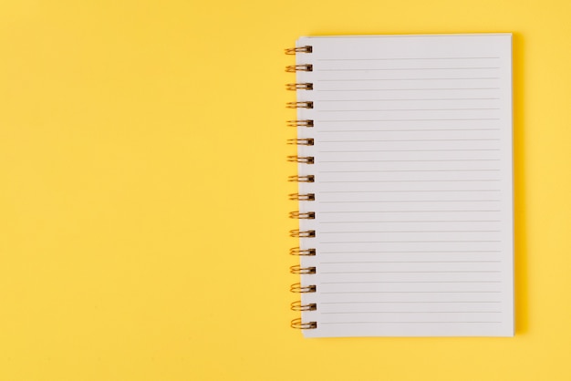 Öffnen Sie das leere Notizbuch auf gelbem Grund. Draufsicht. Platz für Text oder Design.